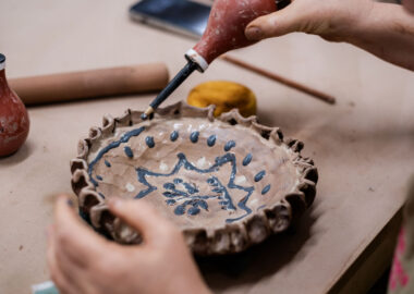 Slip is being applied to a small plate, in the style of Staffordshire slipware.