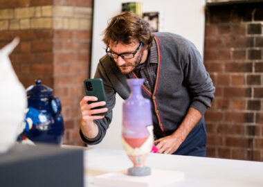 A person is taking a photo of the Fresh exhibition at the 2023 British Ceramics Biennial.