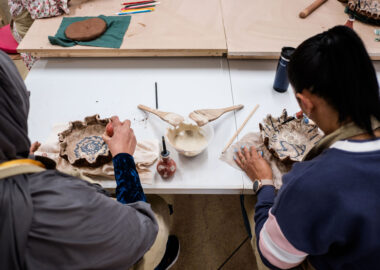 Participants paint clay slip onto some bowls at the BCB Studio.